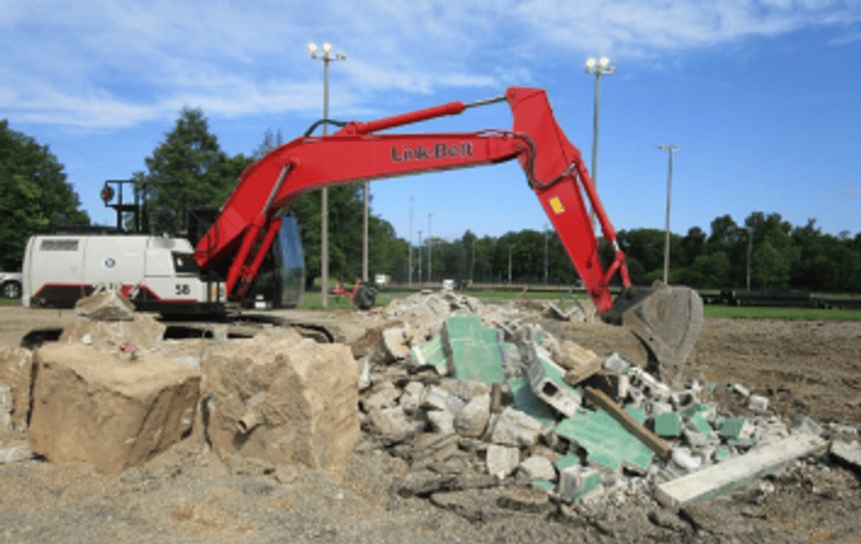 Image is of an excavator at the skatepark site removing rubble and debris.