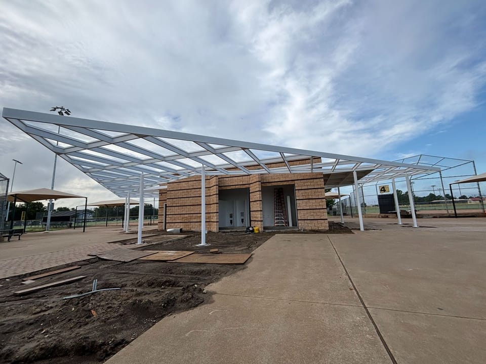 nearly finished restroom building on concrete walkway at baseball park