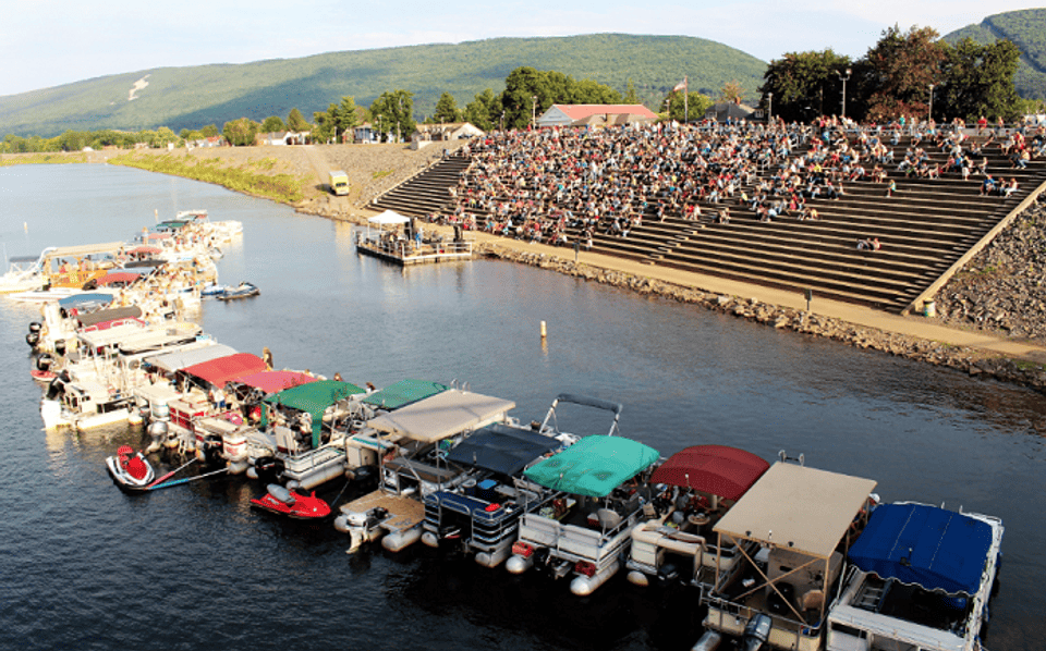 Picture of river and amphitheater with boats, floating stage, and people in the stands