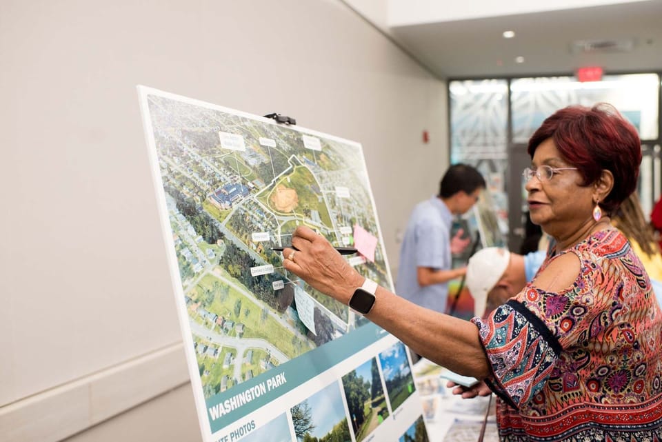 Woman placing Post-It on Washington Park poster during community meeting.