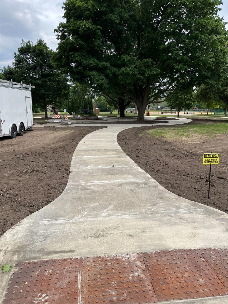 Newly constructed walking paths to the sculpture park with a builders trailer setting to the left of the path. 