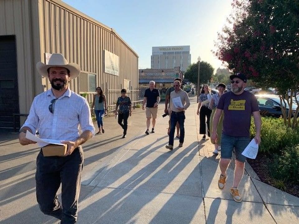 Photo of Planning staff walking with papers in hand next to a building 