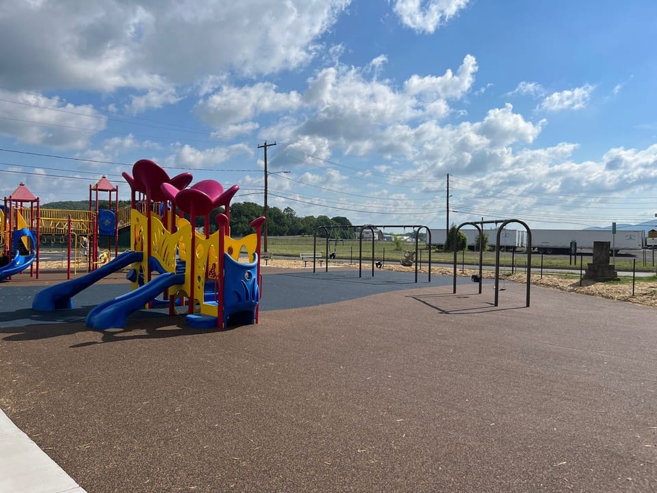 Image showing the updated playground at Piper-Harmon Playground. The image shows the finished fall safe surface in brown and blue color with new swing sets installed in the background.