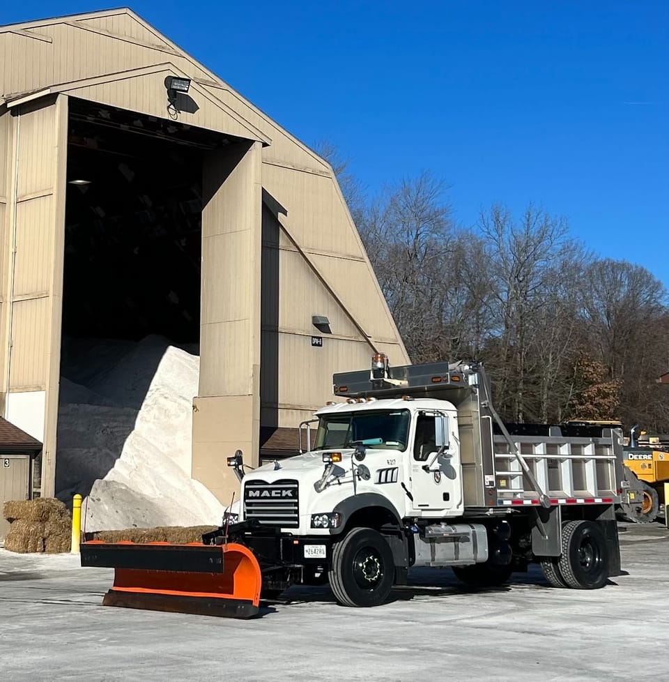 County snowplow parked in front of mound of salt. 