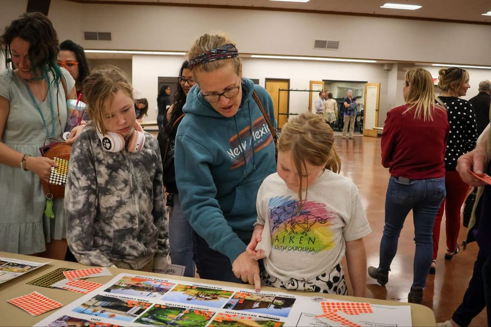 Community members interacting with the workshop activities-- placing stickers on categories that are important to them. 