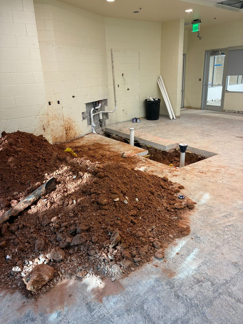 large pile of dirt next to sewer lines and hole in ground