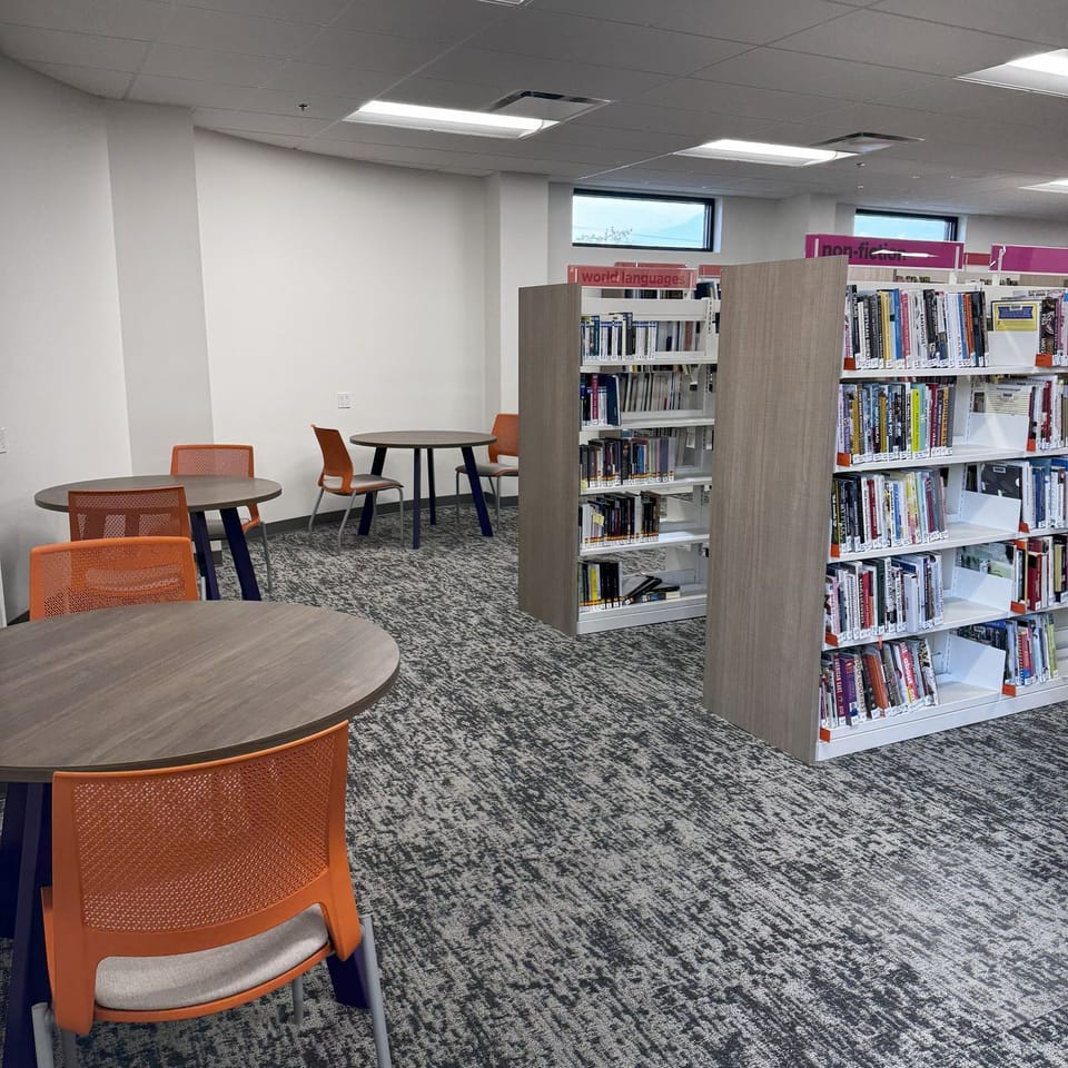Tables and chairs along the west wall of the first floor, in the adult nonfiction collection.