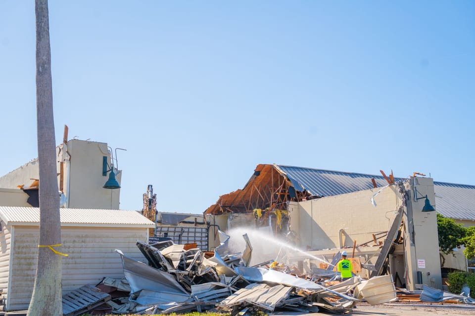 Building being turn down with large pile of debris in front of it